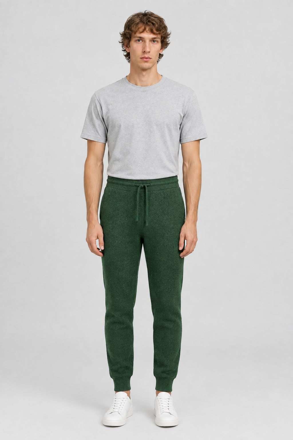 Mannelijk model met de groene About You Joggingbroek Taylan en een lichtgrijs T-shirt, volledig van voren gefotografeerd