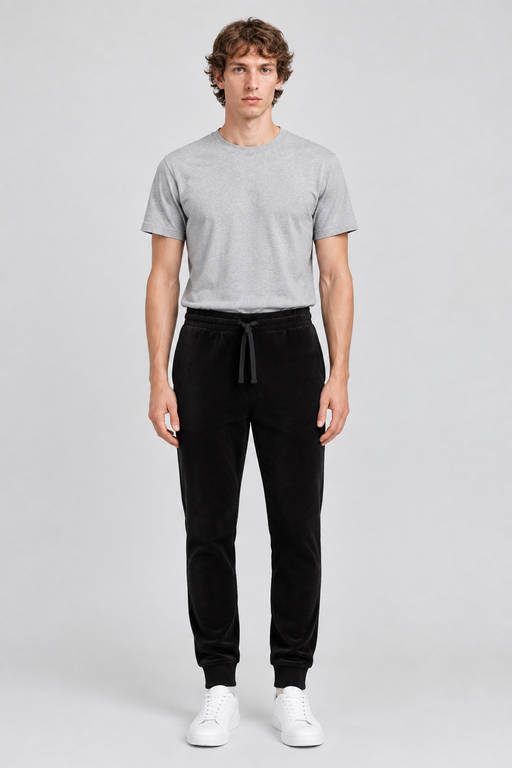 Mannelijk model met de zwarte About You Broek Fernando en een lichtgrijs T-shirt, volledig van voren gefotografeerd