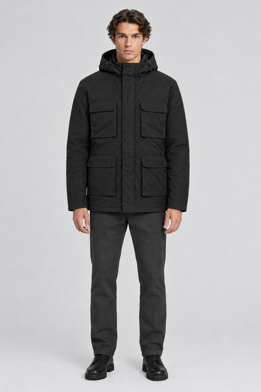 Mannelijk model met de zwarte Dan Fox Apparel Jas Jannik met capuchon en vier klepzakken, volledig van voren gefotografeerd