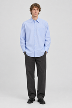 Mannelijk model met het lichtblauw-wit gestreepte Jack & Jones Oversized Overhemd Bill Poplin, volledig van voren gefotografeerd