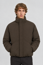 Vooraanzicht van een mannelijk model met de donkerbruine Only & Sons Puffer Jas Josh met gladde buitenkant en hoge kraag